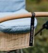NATURKIND Kinderwagen Ida - erhältlich bei Hautnah Naturwaren Eine Nahaufnahme von einem braunen Griff eines Kinderwagens. In der Mitte ist ein Anhänger mit der Aufschrift "NATURKIND".